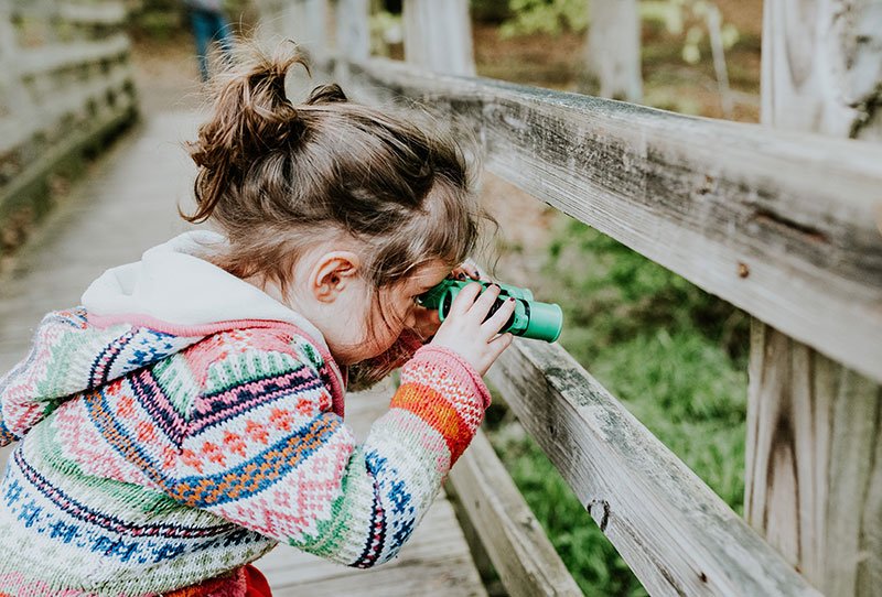 niña avistando aves con prismáticos