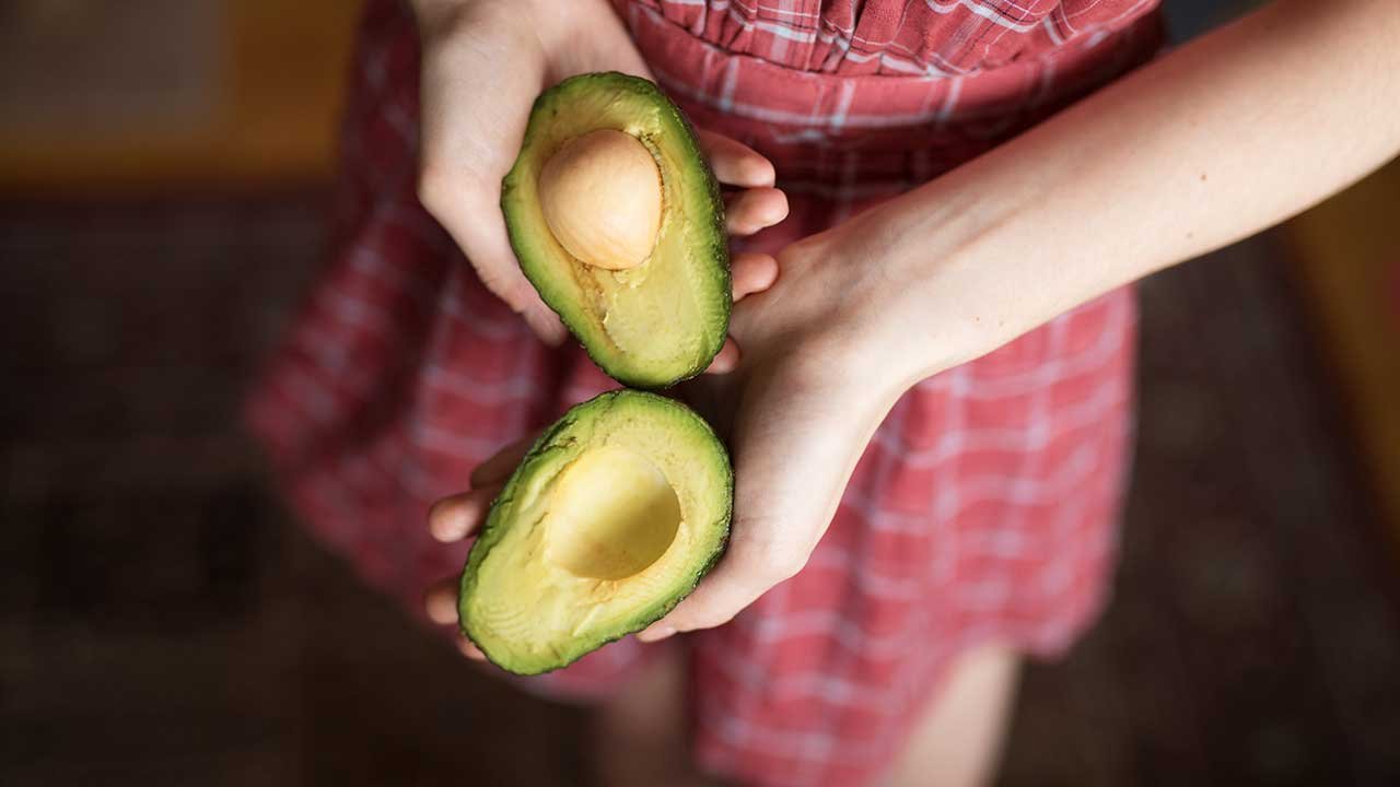 Mujer abriendo un aguacate para conseguir su hueso