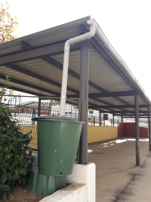 Depósito de agua reciclada para riego de huerto ecológico en centro educativo.