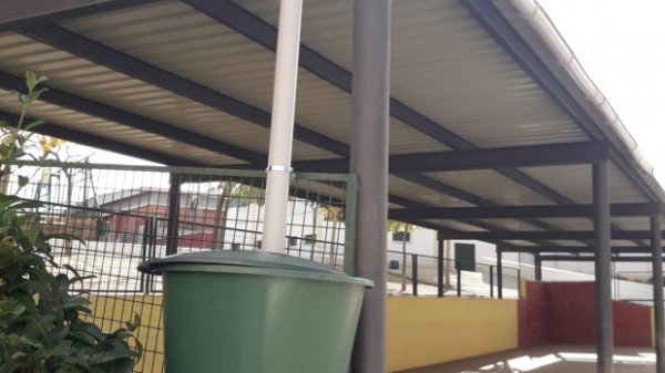 Depósito de agua reciclada para riego de huerto ecológico en centro educativo.
